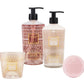 The Baobab Collection Paris Body Wellness Collection features a candle, lotion, liquid hand soap, and round pink soap with gold geometric designs, all infused with a Paris scent of wisteria and chestnut bloom.