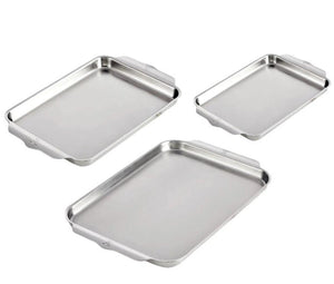 Three Hestan Provisions OvenBond Sheet Pans, made of triple-bonded clad stainless steel, are arranged diagonally on a white background. These versatile pans are oven safe up to 600°F for all your baking needs.