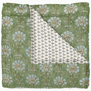 The Jeeva Sage Bedding Collection by John Robshaw showcases a sage green quilt with large blue and white florals, hand quilted for charm. A folded corner reveals a white cotton voile underside with small green and brown floral motifs.