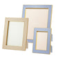 Three empty rectangular frames from Aerin’s Classic Croc Leather Frame Collection, crafted from Italian croc-embossed leather in beige and light blue, stand upright against a white background.