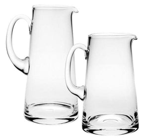 The Classic Pitcher Collection by William Yeoward Crystal features two clear glass pitchers with handles, displayed side by side against a white background—ideal for serving water or fruit juice.