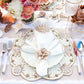 A formal table setting with a Kim Seybert Beachcomber Placemat, white napkin and ring, floral centerpiece, glassware, and silverware on a striped tablecloth—ideal for elevating any coastal home.