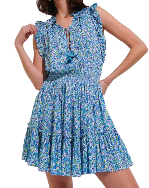 Woman posing in a blue floral Poupette St Barth Triny Mini Dress with ruffled sleeves and smocked waist.