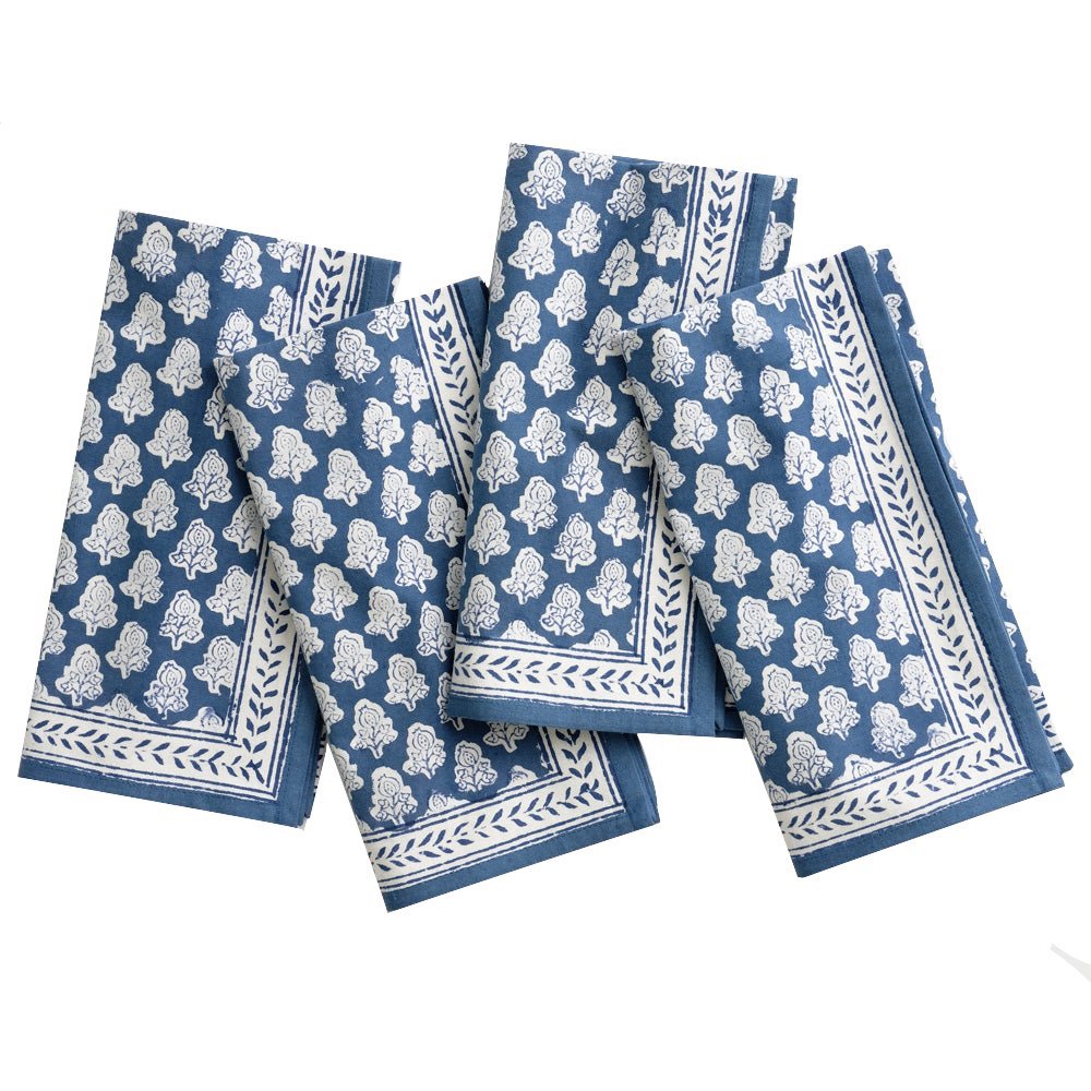 Four blue and white patterned cloth napkins from the Pomegranate Inc Pom Buti Denim Collection are arranged side by side, enhancing the dining experience with their subtle floral design.