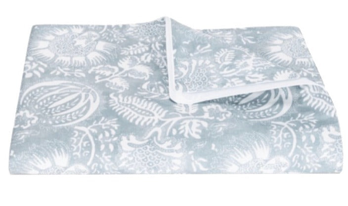 The Matouk Granada Bedding Collection in Hazy Blue is shown folded on a white background, featuring a blue and white floral pattern crafted from Egyptian cotton percale and OEKO-TEX certified.