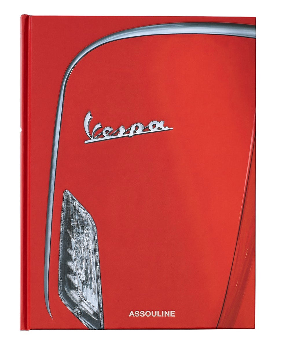Close-up of a red Vespa's front—with its iconic logo and headlight—featured on the cover of the Assouline Vespa book, an elegant homage to classic Italian design and culture.