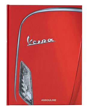 Close-up of a red Vespa's front—with its iconic logo and headlight—featured on the cover of the Assouline Vespa book, an elegant homage to classic Italian design and culture.