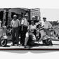 A group of six men pose in front of Vespa scooters outside a building, depicted in a black-and-white photograph showcased in the open pages of the "Vespa" book by Assouline—capturing the timeless allure of Italian culture.