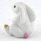 The Herend Bunny with Cross is a sitting ceramic figurine featuring hand-painted pink and gold accents on its ears and feet, reminiscent of Herend porcelain artistry, against a plain white background.