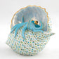 Herend Reserve Collection Multicolor Octopus in Shell: Porcelain figurine of a vibrant octopus nestled in a shell, detailed with white, green, and blue scale-like patterns and shimmering pearlized paint.