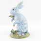 The Herend Reserve Collection Anniversary Bunny features a blue and white patterned rabbit with a bird on its paw, standing on a floral base with leaves and butterfly accents, showcasing exquisite hand-painted designs.