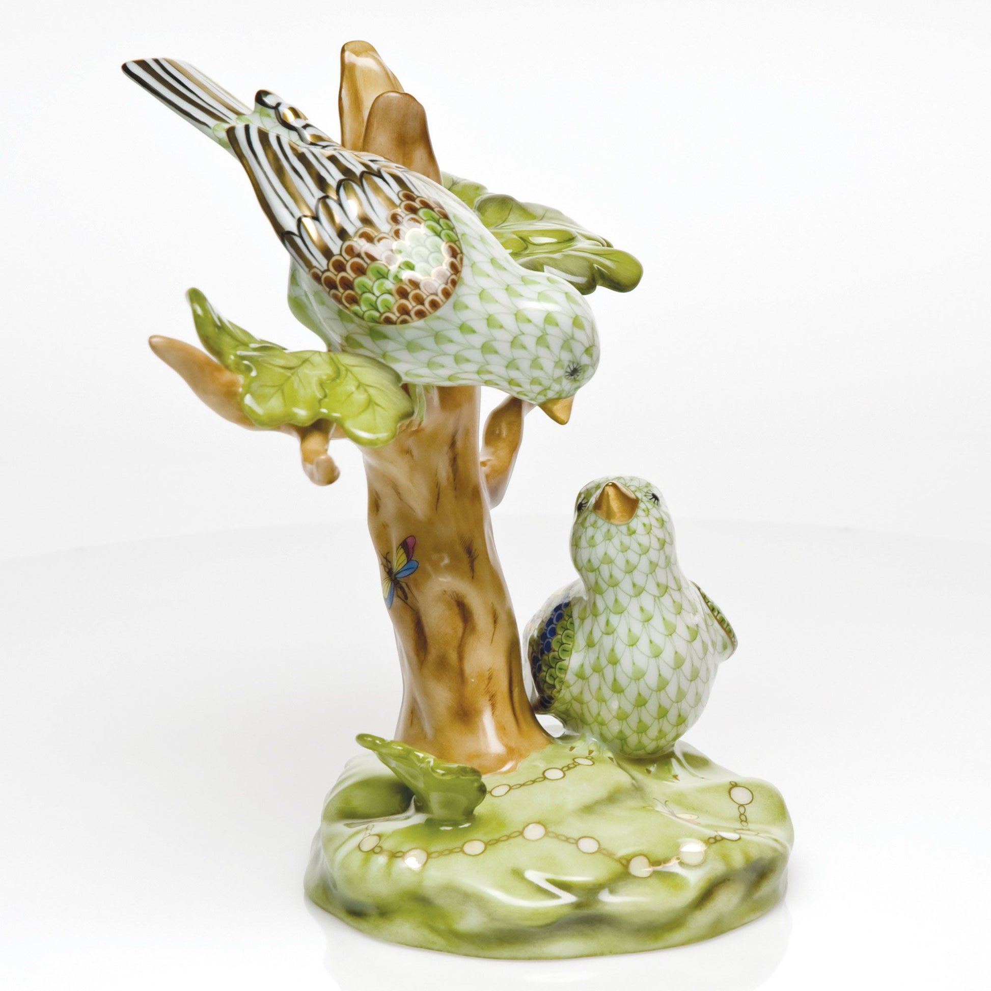The Herend Reserve Collection The Rothschild Birds is a limited edition collectible featuring two green and white birds on a brown stump with green leaves, set on a glossy green base.