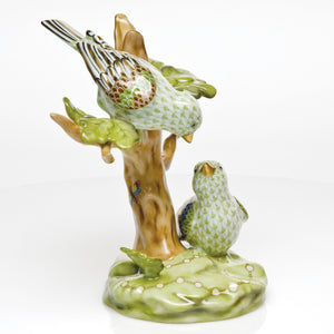 The Herend Reserve Collection The Rothschild Birds is a limited edition collectible featuring two green and white birds on a brown stump with green leaves, set on a glossy green base.