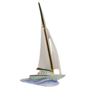 The Herend Sailboat is a porcelain figurine with gold-accented sails, a green patterned base, and a blue wave platform—a timeless decorative accent for any space.