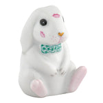 The Herend "Bunny Kisses" figurine is a handcrafted Hungarian porcelain bunny with pink lipstick marks, a green patterned bow tie, and pink accents on its nose and feet.