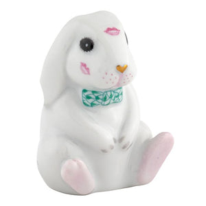 The Herend "Bunny Kisses" figurine is a handcrafted Hungarian porcelain bunny with pink lipstick marks, a green patterned bow tie, and pink accents on its nose and feet.