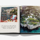 An open book from Assouline displays a breakfast table scene on the left page and, on the right, a breathtaking coastal cliff landscape with houses above blue water, evoking the luxurious views enjoyed at Villa Treville Positano.