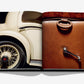 An open spread of Assouline's "Vintage Cars (2nd Edition)" showcases a detailed close-up of a classic car’s rear wheel on the left page and a brown leather car door with its handle on the right, beautifully embodying the essence of luxury automotive photography.