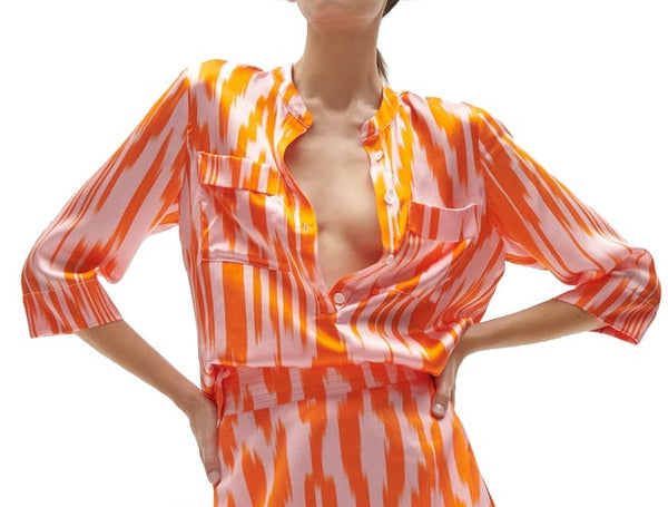 Woman posing with hands on hips wearing a Figue Vega Top, a silk charmeuse, orange and white striped shirt with a band collar.