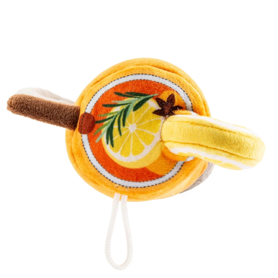 The Haute Toddy Dog Toy by Haute Diggity Dog is a plush toy shaped like a round citrus slice, featuring a handle, fabric garnish accents, an interactive squeaker, and an attached looped string.