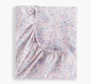 The Gooselings Enchanted Wildflowers Crib Sheet, featuring a pastel floral pattern and elastic edges, OEKO-TEX certified, is shown folded on a plain white background.