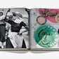 An open book, Wine & Travel Mediterranean Islands by Assouline, displays a black-and-white photo of dancers opposite a colorful table setting with a plate featuring a face—capturing the vibrant spirit of Mediterranean island wines.