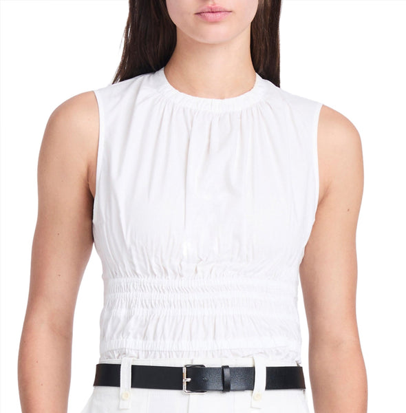 A woman in a white sleeveless Proenza Schouler Birdie Top with a smocking bodice and a black belt, only her upper torso is visible.