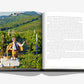 An open copy of *Wine & Travel Italy* by Assouline features a picturesque Italian vineyard scene on the left page with a person savoring wine in a manner reminiscent of Enrico Bernardo's tastings, paired with text on the right page.