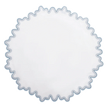 The Matouk Wave Tabletop Collection in Hazy Blue features a round white linen tabletop with a wavy blue embroidered edge and is OEKO-TEX certified for safety and style.