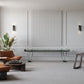 Modern living room with leather chairs, a small chess table, a large plant, wall paneling, open shelving, and the Scivolo Shuffleboard Game Table by Impatia—all reflecting exquisite Italian craftsmanship.