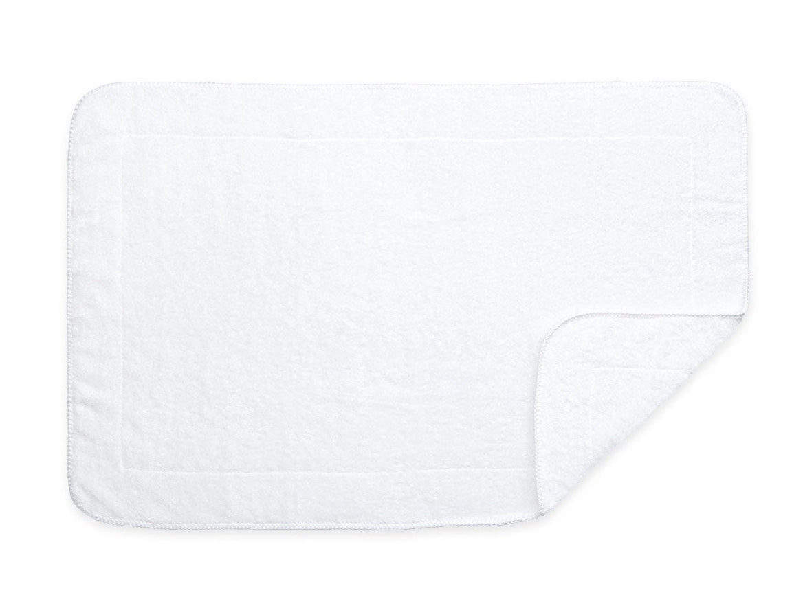 A rectangular white towel from the Matouk Whipstitch Bath Collection, crafted with Cairo long-staple cotton, has one bottom corner folded over and is set against a plain white background.