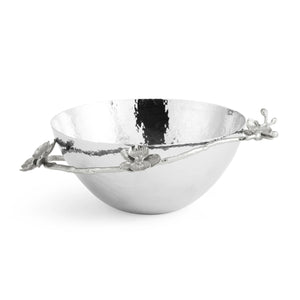 A silver hammered metal bowl from the Michael Aram White Orchid Serveware Collection, featuring decorative branches and flower accents on the rim, evoking purity and subtle mystery.