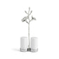 The Michael Aram White Orchid Serveware Collection features white ceramic salt and pepper shakers in a silver, flower-adorned branch holder, capturing purity and subtle mystery against a plain white background.