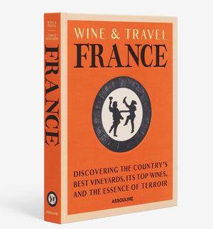 The hardcover book "Wine & Travel France" by Assouline, adorned with an orange cover and a circular illustration, delves into French vineyards, wines, and terroir. It offers insights on wine tourism with contributions from Enrico Bernardo.