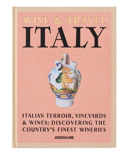 The book cover titled "Wine & Travel Italy" from Assouline showcases an illustrated vase adorned with a scenic design. The subtext, "Italian Terroir, Vineyards & Wines: Discovering the Country's Finest Wineries" by Enrico Bernardo, pays homage to Italian vineyards and wine tourism experiences.