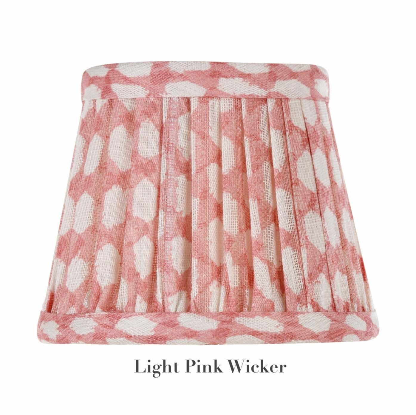 The Zafferano x Fermoie Poldina Lampshade Collection by Zafferano America offers a pleated design with a light pink wicker pattern and white ovals on textile, capturing the elegance of Fermoie's style.