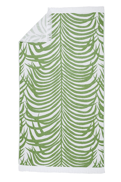 The Zebra Beach Towel Collection by Matouk features a rectangular towel with a green tropical leaf pattern on white, accented with white fringe on the short edges.