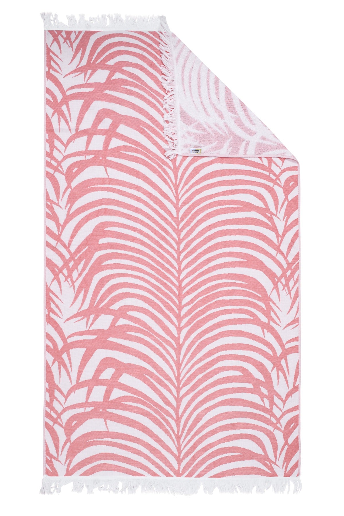 Matouk’s Zebra Beach Towel Collection features a rectangular towel with a pink and white palm leaf pattern, white fringe on two sides, and a folded corner—ideal for relaxing in tropical style.