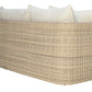 The Zeya Outdoor 3 Seater Sofa by Janus et Cie features beige, weather-resistant wicker and white cushions, shown angled from the back against a white background. This elegant piece brings comfort and style to any patio or garden.