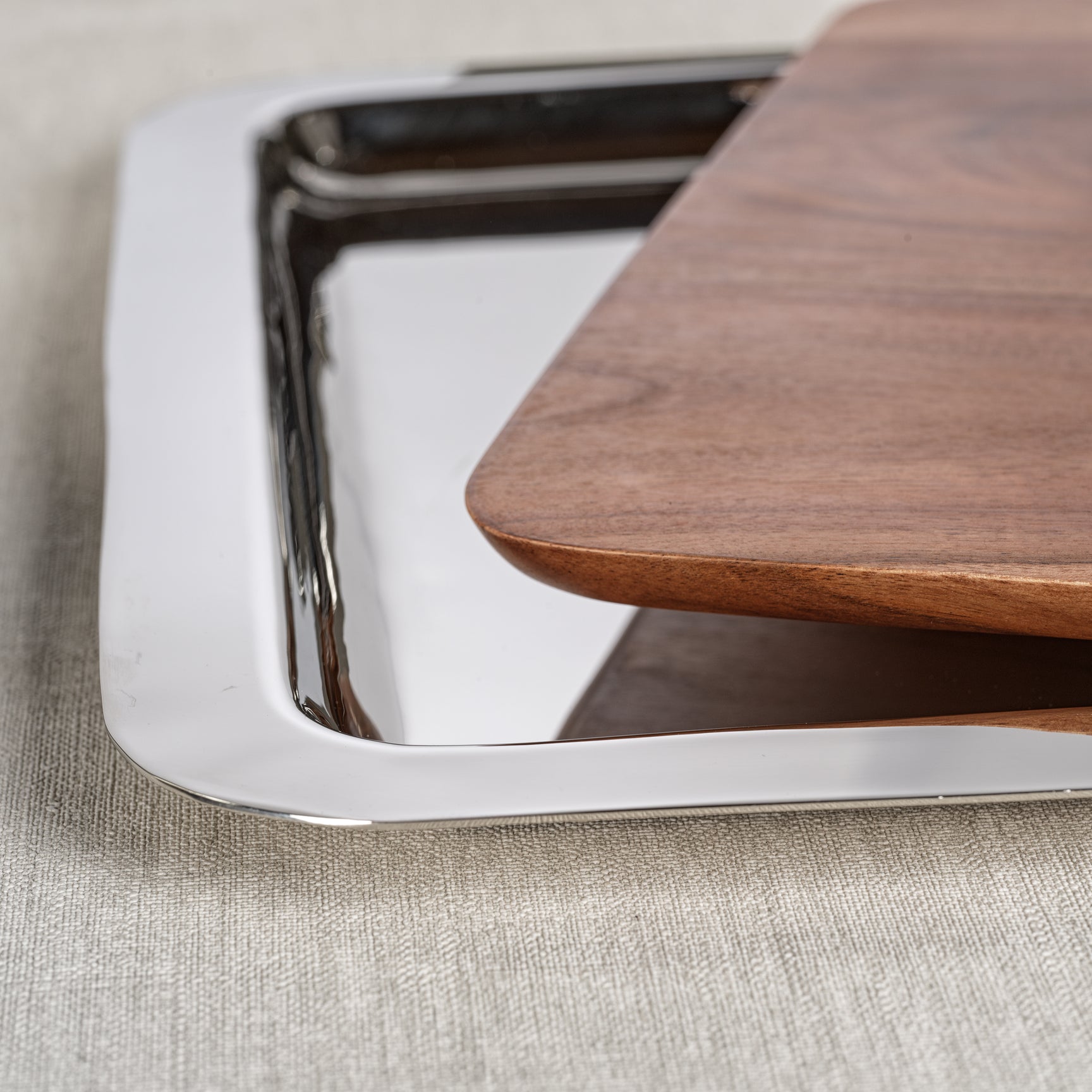 The Zodax Brasserie Steel and Acacia Wood Gastronomy Board Collection features a rectangular metal tray topped with an acacia wood cutting board—ideal for serving charcuterie on any light-colored surface.