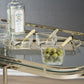 A glass bar cart displays a bottle of Bombay Dry Gin and the Zodax Roussillon Condiment Set—two empty glass bowls with gold-handled spoons, plus a third bowl filled with green olives.