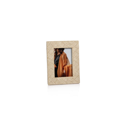 The La Bocca Frame Collection by Zodax features a natural, chic beige photo frame crafted from woven raffia, shown displaying a partial image of a long-haired person in orange against a plain white background.