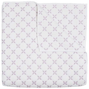 The John Robshaw Layla Lavender Coverlet is a white cotton voile quilt featuring intersecting lavender circles and floral motifs inspired by Mughal gardens, shown neatly folded with one corner turned down.