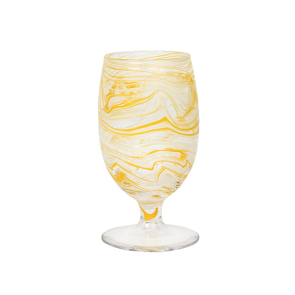 The Juliska Puro Marbled Drinkware Collection features a clear-stemmed goblet with yellow and white swirled glass, evoking seaglass tones, shown against a plain white background.