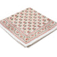 A folded beige cloth napkin from the Alwar Table Linen Collection by SLOANE BY HAND, featuring hand block printed red and green florals with a decorative border—ideal for mixing and matching with your favorite tableware.