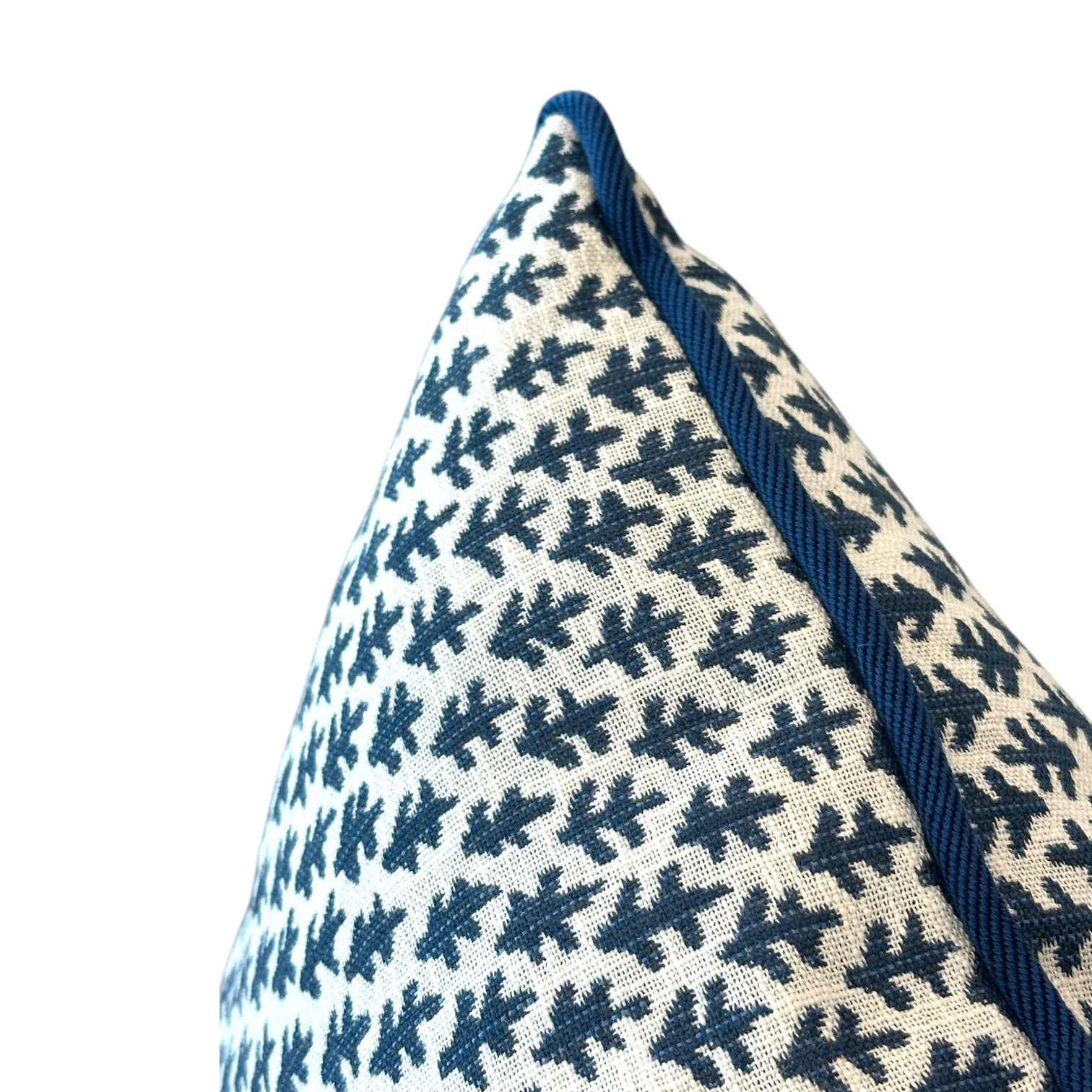 Close-up of the Burma White Indigo Outdoor Pillow by Associated Design, showcasing a blue leaf-like pattern and piped edge on a white background, crafted from premium materials against a plain backdrop.