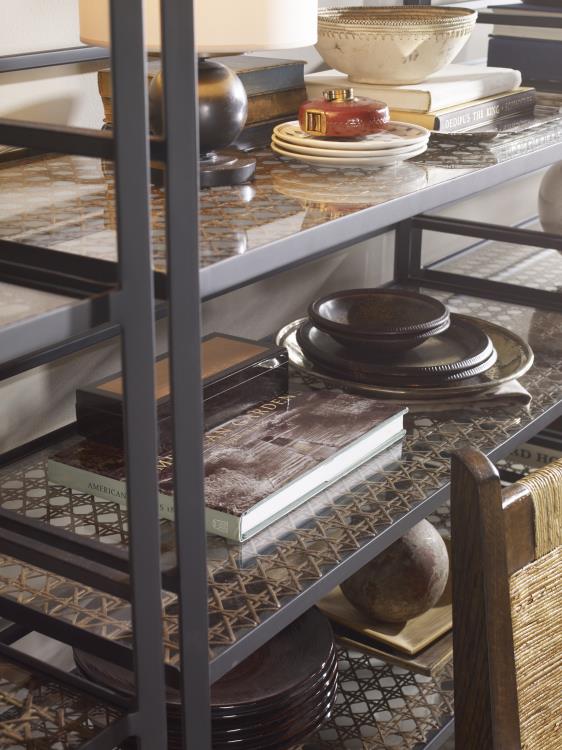 The Tom-Tom Etagere by Century Furniture displays stacked dark dishes, books, decorative objects, and bowls. In the foreground, a wooden chair and nesting tables are partially visible.
