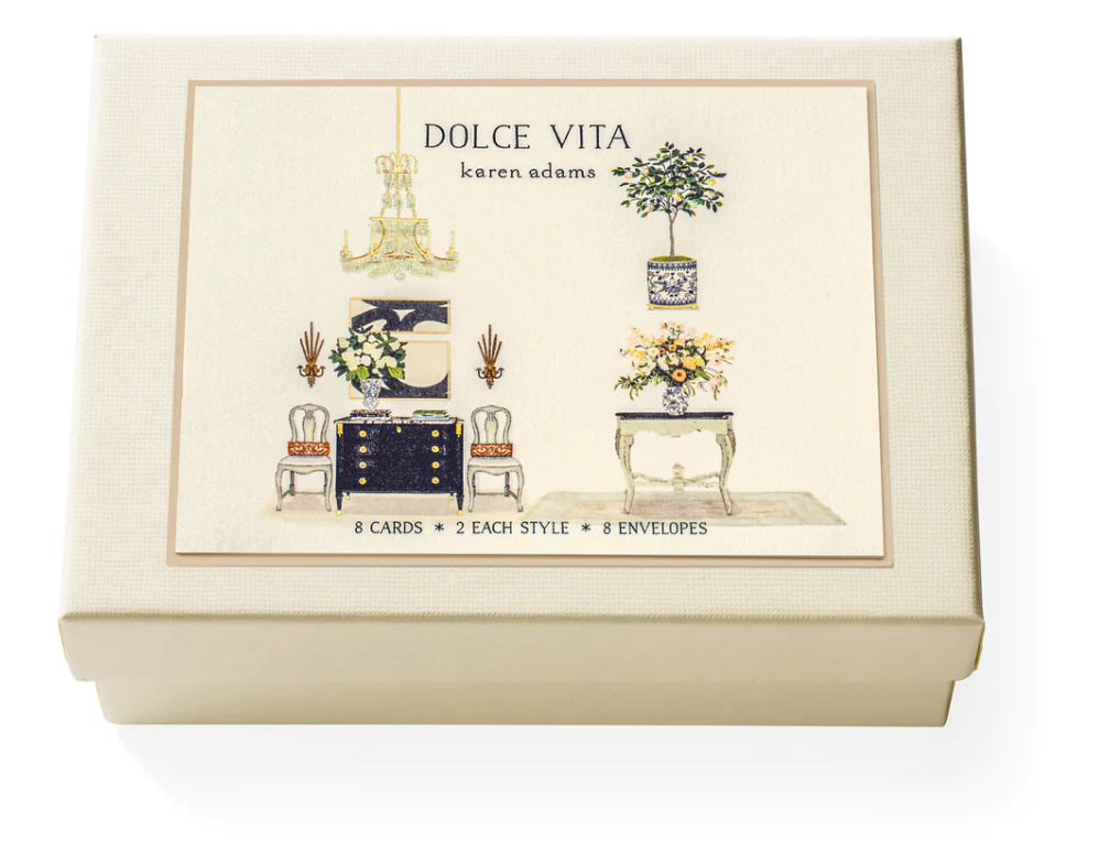 The Karen Adams Dolce Vita Card Set includes a cream-colored box with hand-embellished furniture and floral designs, holding 8 natural white note cards (2 styles) and 8 envelopes—an ideal gift for any hostess.