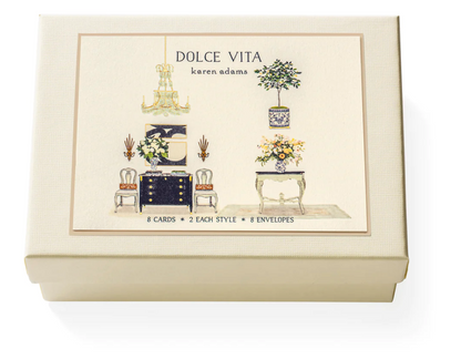 The Karen Adams Dolce Vita Card Set includes a cream-colored box with hand-embellished furniture and floral designs, holding 8 natural white note cards (2 styles) and 8 envelopes—an ideal gift for any hostess.