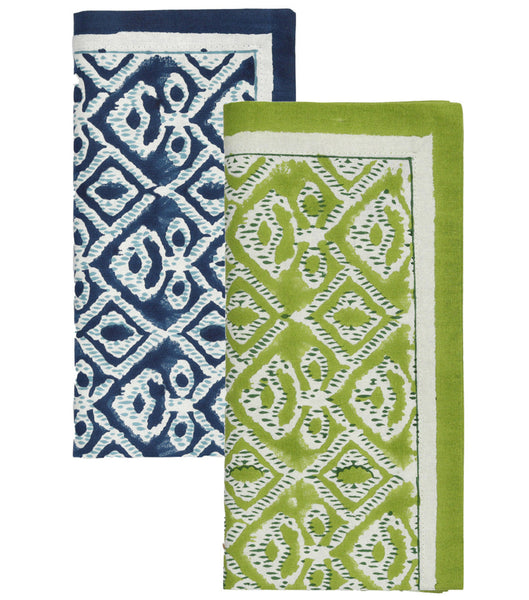 The Kim Seybert Alfresco Napkin Set features two elegantly folded cotton napkins with intricate white and dark blue, along with white and green patterns, showcasing symmetrical block printing designs.